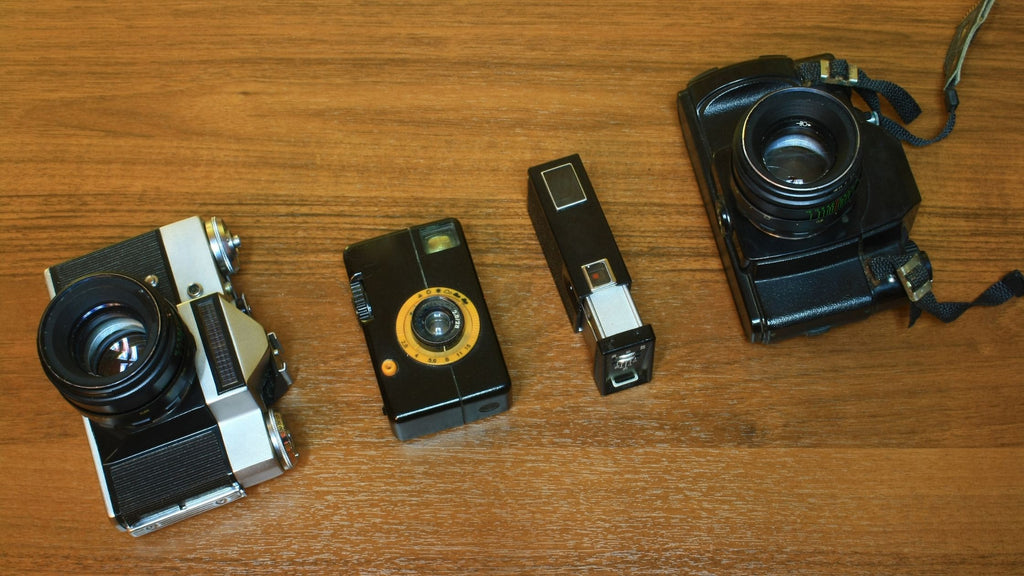 A photo of four different kinds of analog cameras. 