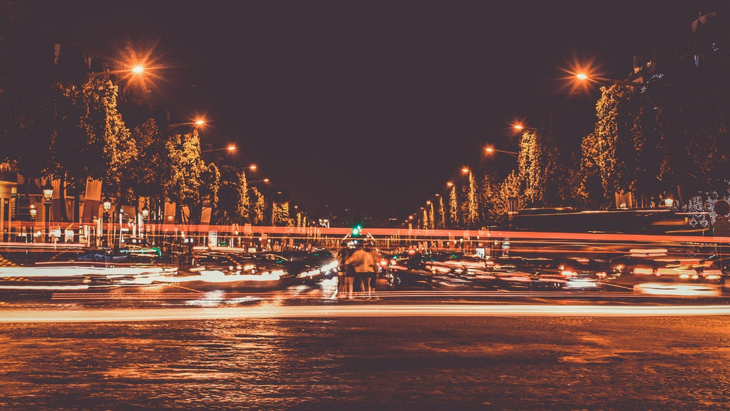 A group of people standing still in the middle of a very busy intersection. 