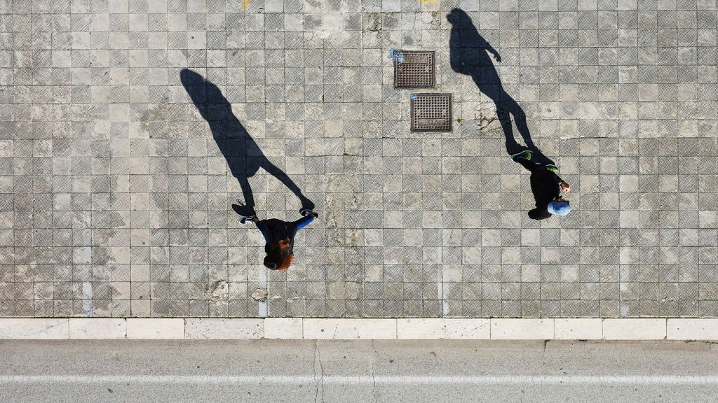 A photo taken from the top that perfectly displays peoples shadows while they walk. 