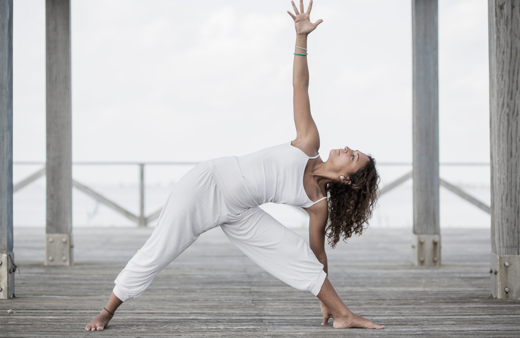 Woman practicing triangle pose on pier