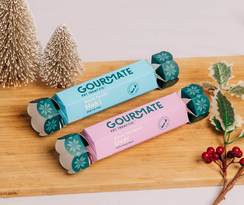 Two Gourmate Dog Treat Christmas Crackers on a wooden board with Christmas decorations