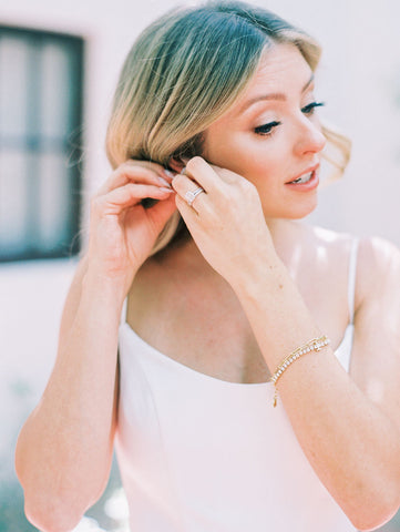 Bride puts on earrings as she gets ready.