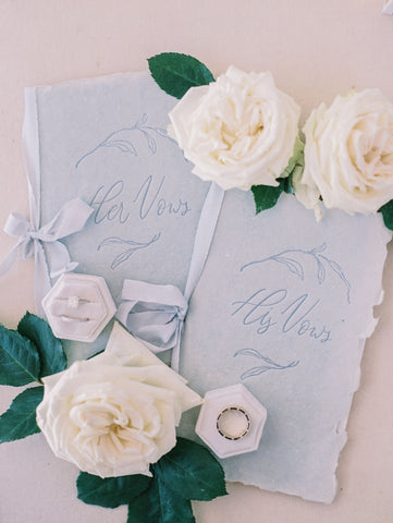 His and hers vows in baby blue books tied with ribbon.