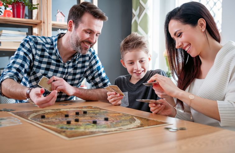 Happy family comparing cards from board game at living room table