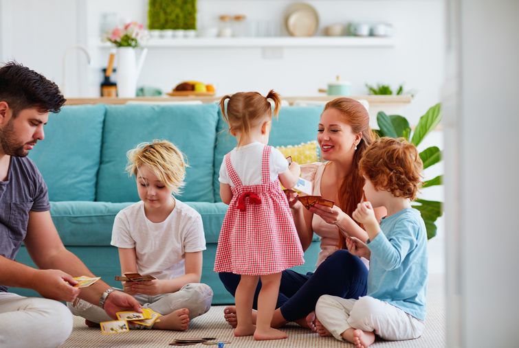 Happy family playing card game together on living room carpet