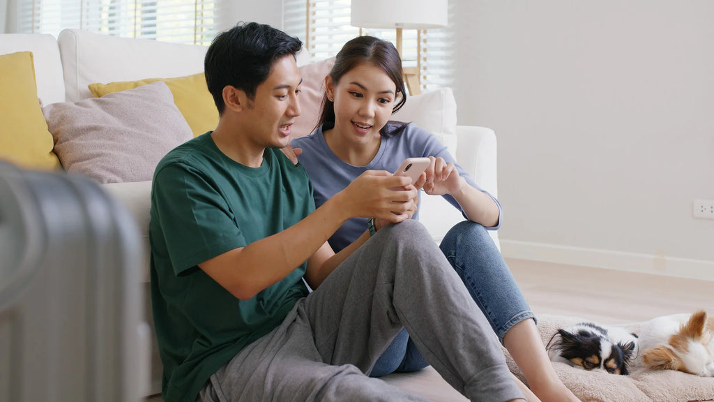 couple-looking-for-something-in-mobile-phone-with-their-pet-dog-on-the-side