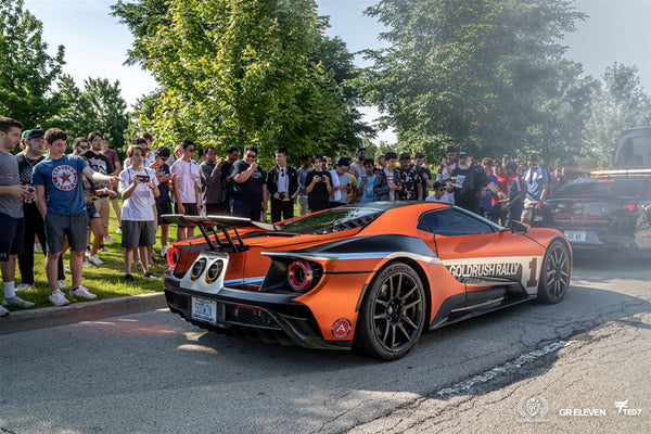 A crowd looks on at an orange supercar