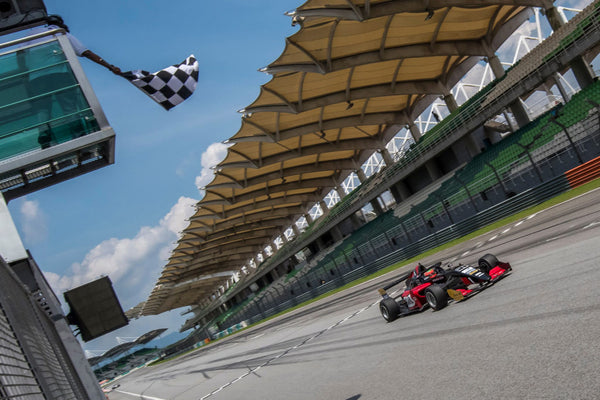 The checkered flag is waved from above as the red Oloi F3 car crosses the finish line