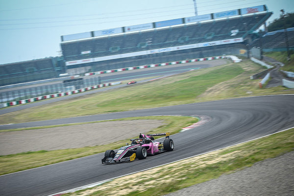 The pink Oloi F3 car navigates a turn on Suzuka International Circuit