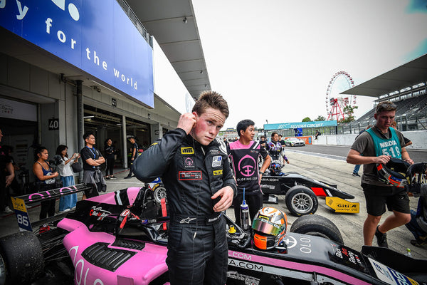 Driver Brendon Leitch stands in front of the pink Oloi F3 car outside the BlackArts Racing garage