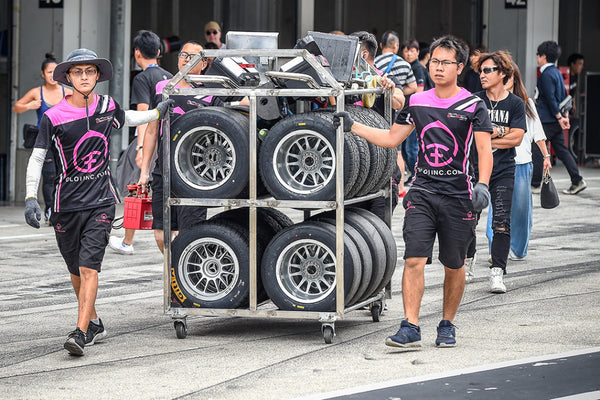 BlackArts Racing technicians wheel a rack of racing tires in the staging area at Suzuka International Circuit