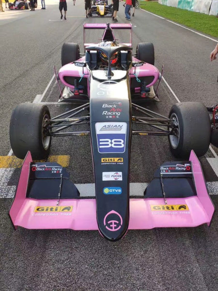 Head-on view of the pink Oloi F3 car and driver on the starting grid