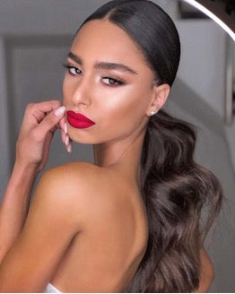 tanned lady wearing red lipstick with brown loose wave ponytail and middle parting