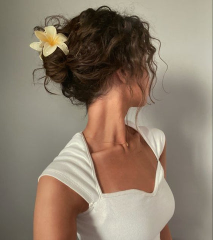 Curls in messy bun hairstyle with flower claw clip accent