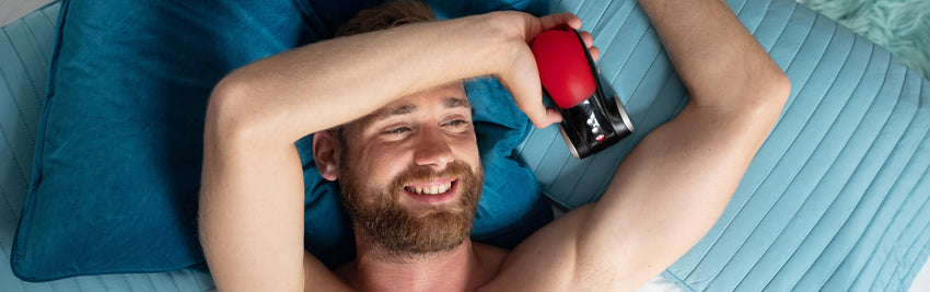 Man laying in bed holding Cobra Libre II by Fun Factory