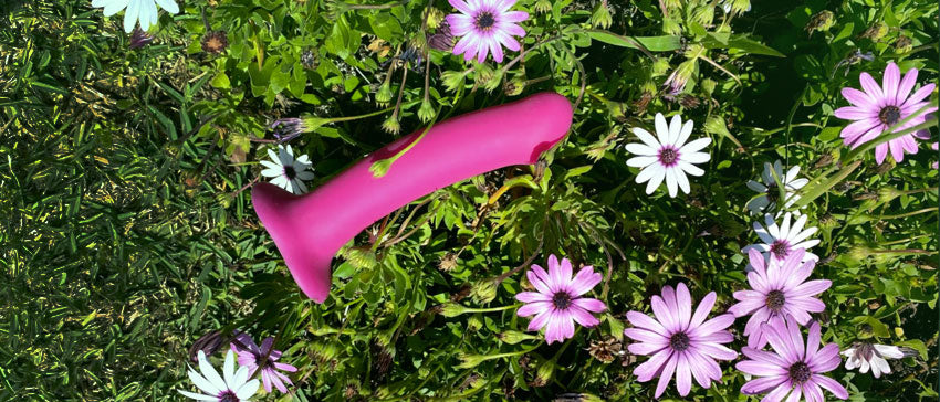 Image of MAGNUM Dildo in pink laying in flowered bushes