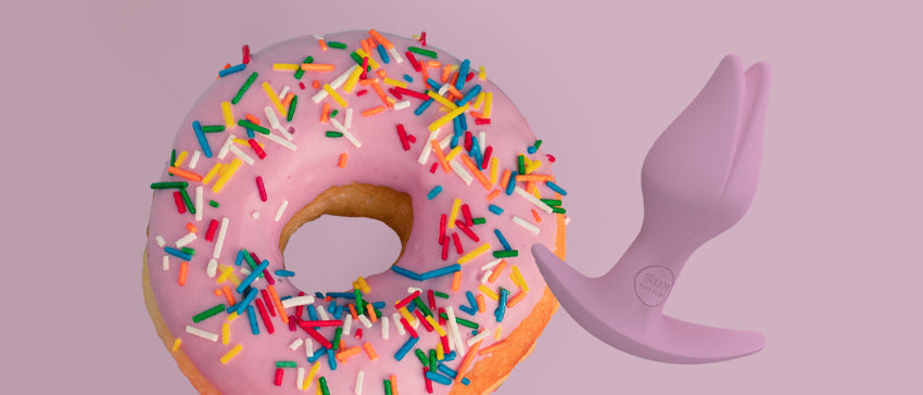 Bootie Fem butt plug by Fun Factory next to a donut on a pink background