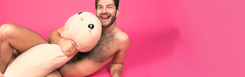 Zachary Zane smiling and holding his penis shaped plushie