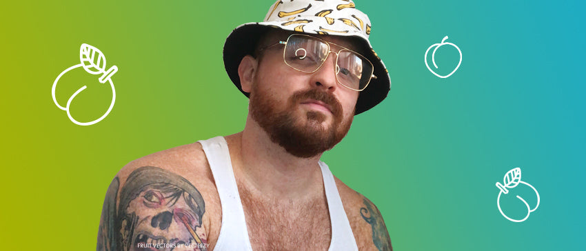 Headshot of writer wearing sunglasses and a hat with bananas on it