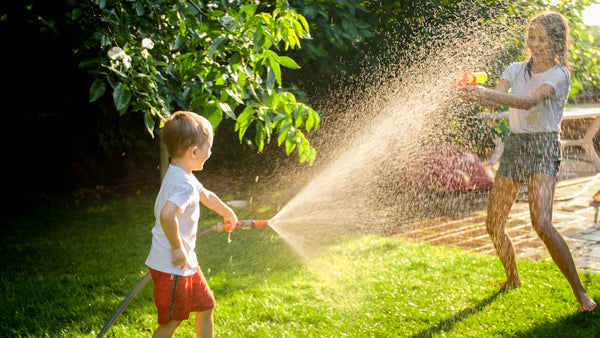 Brother and sister having a water fight in the garden