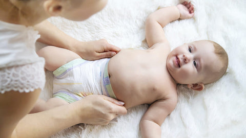 baby smiling at person laying on changing mat
