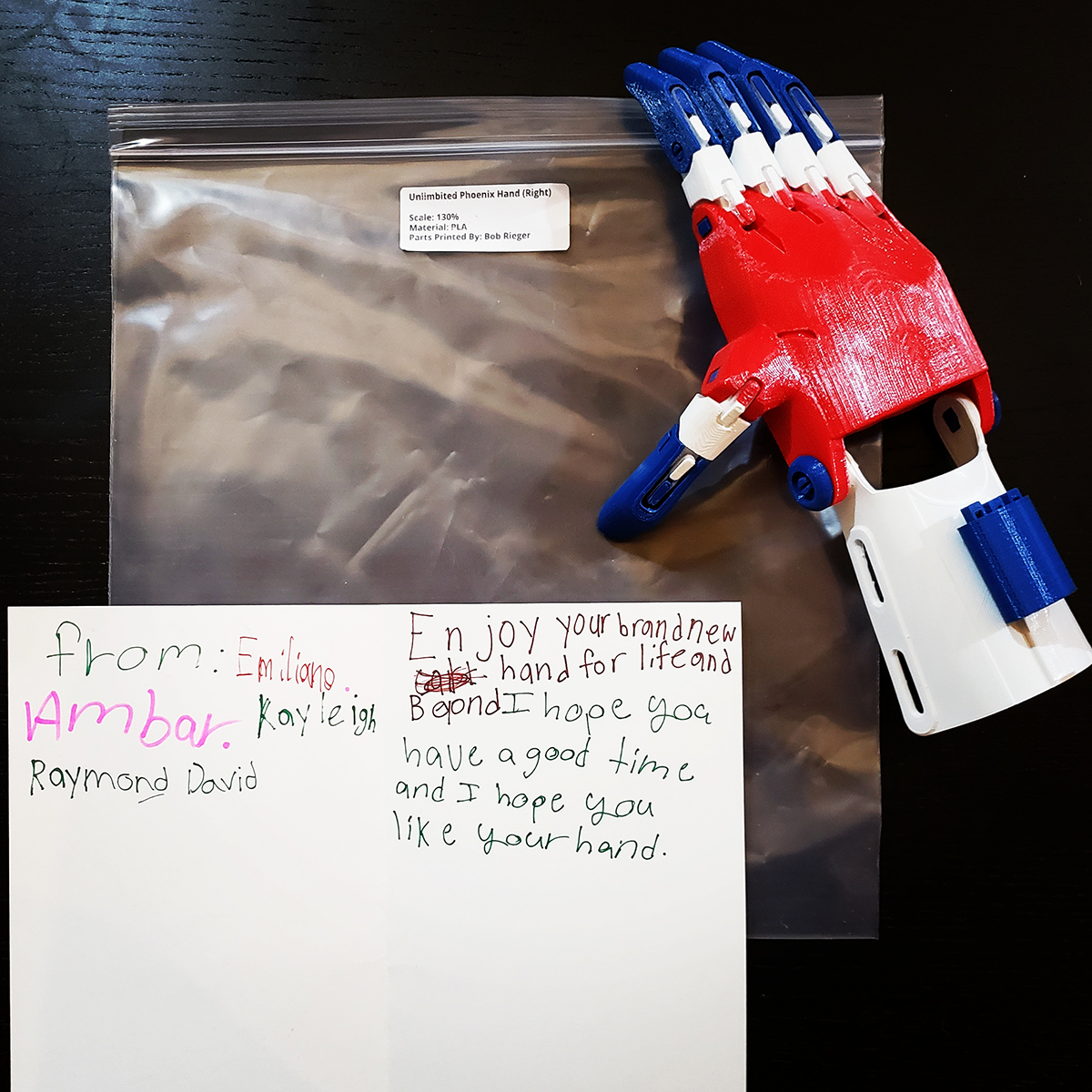 A completed 3D printed e-NABLE hand with a note from Peck Elementary School Students who assembled it for them