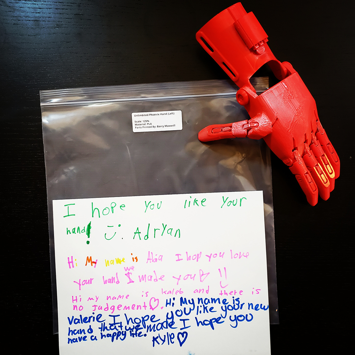 A completed 3D printed e-NABLE hand with a note from Peck Elementary School Students who assembled it for them