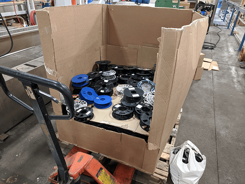 Recycling 3D printing filament spools shown in a box on a pallet