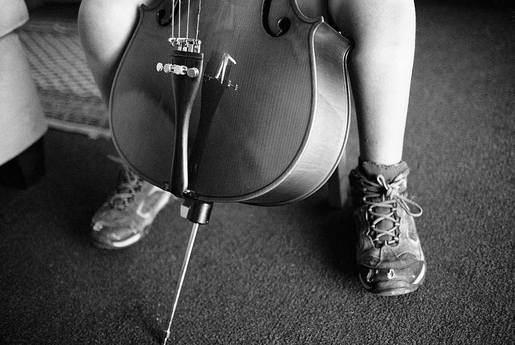 Film photo by Katie Lobodzinski of a child in hiking boots playing a cello