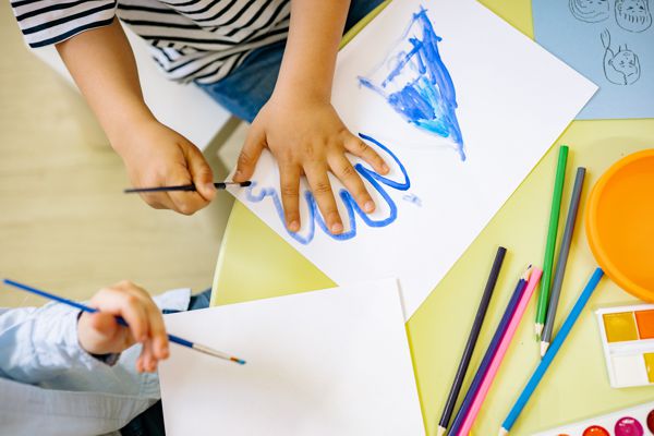 Kinder malen mit Schürze ein Bild mit Farbe
