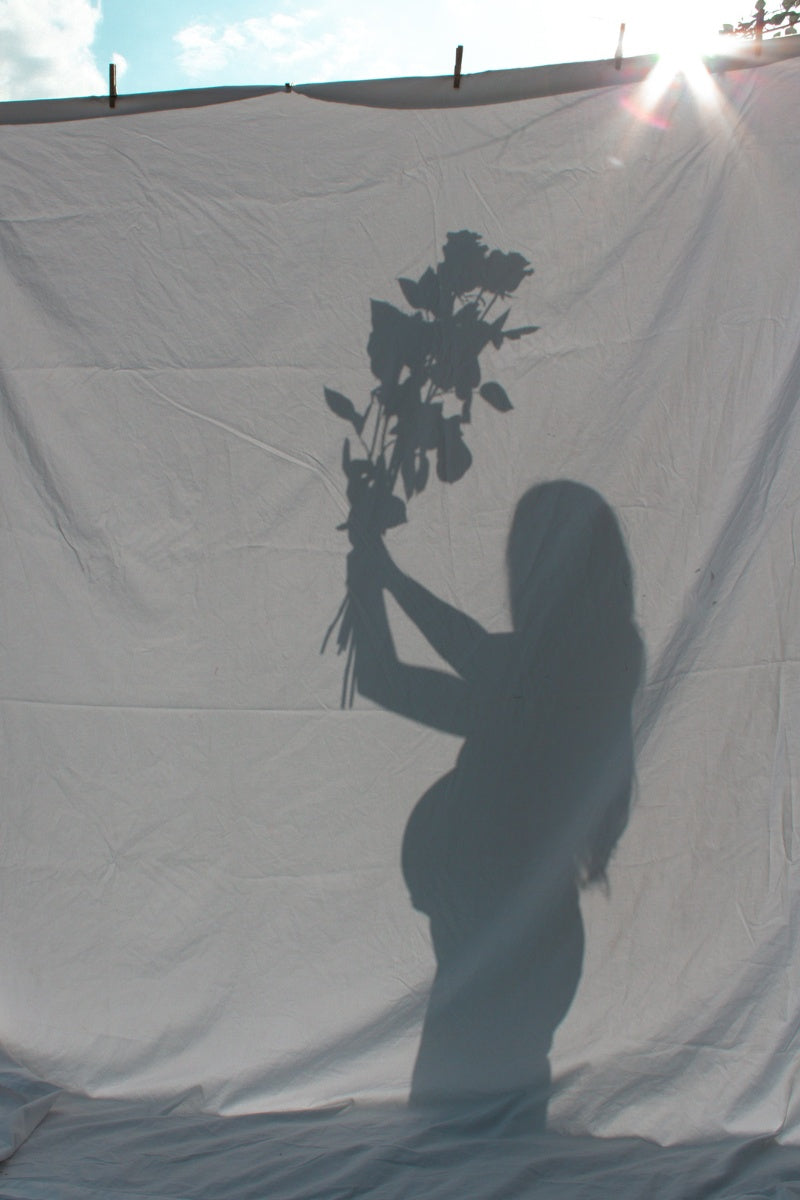 allison behind a sheet creating a beautiful shadow of her with flowers