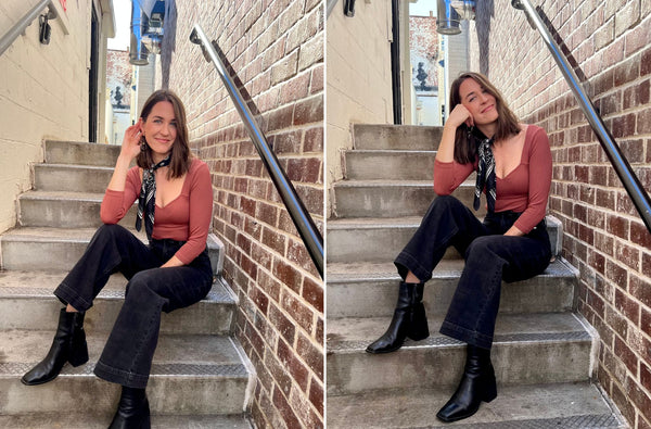 Haley wearing the cecelia basic long sleeve top in orange. She is sitting in a stairway outside on a sunny day. she is wearing a black bandana and black denim and smiling because she is happy and loves her outfit.