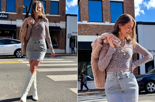 Haley is standing near a crosswalk on 21st Ave. South in Nashville Tennessee. She is wearing a purple lace top and white knee high boots and a denim skirt. She had a fur jacket on over her sholder. She is smiling because it's a beautiful sunny day and she loves her outfit.