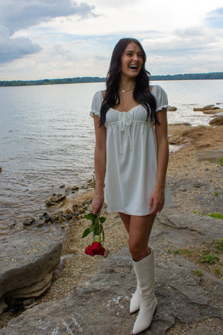 laken wearing a white dress and white boots by the lake