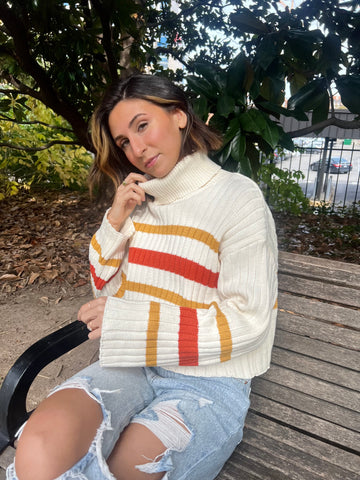 Model lauren sitting on a park bench in Nashville TN wearing a turtle neck sweater and distressed denim.