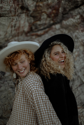 two girls with curly hair and hats 