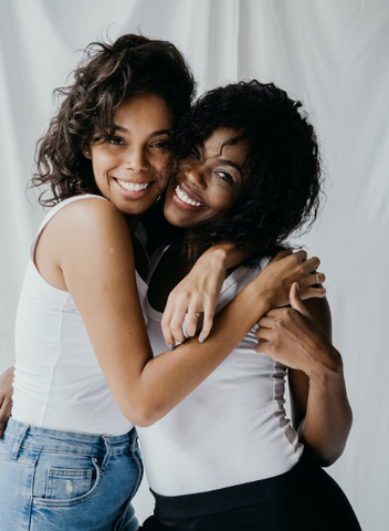 two women with curly hair hugging