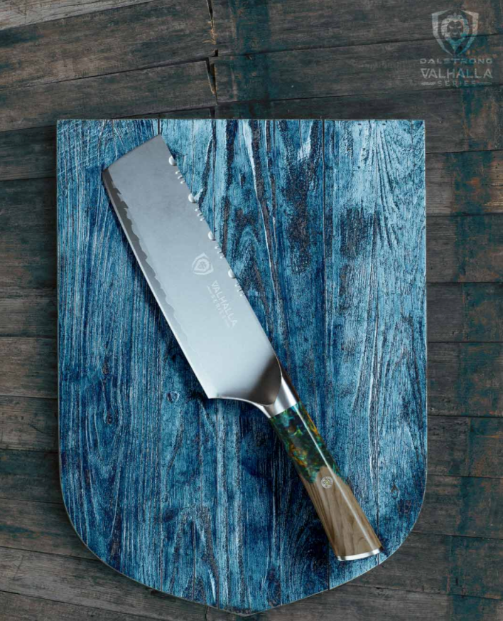 Nakiri knife on a teal green cutting board against a wooden background