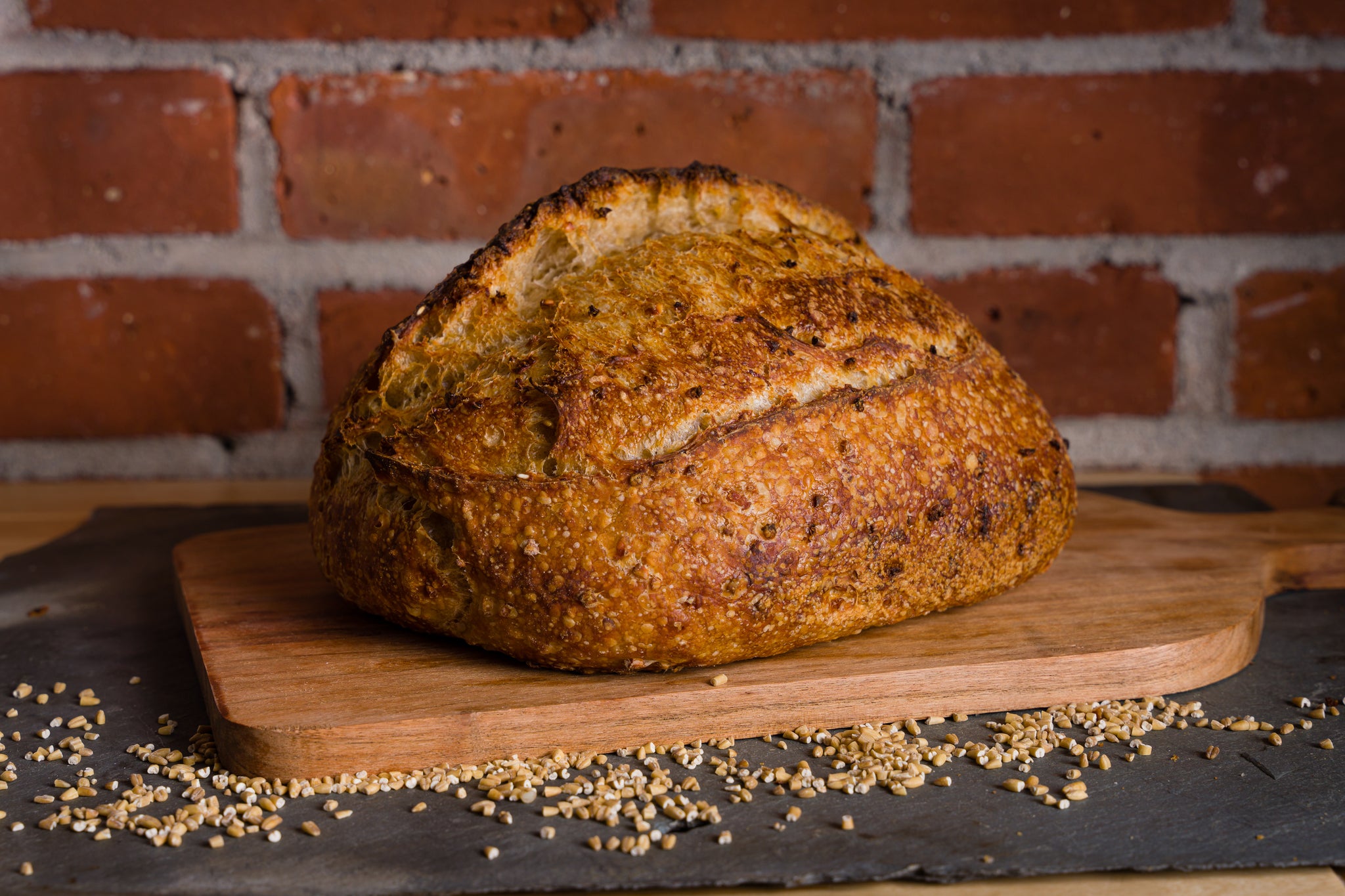 A whole loaf of oatmeal porridge bread on a wooden cutting board