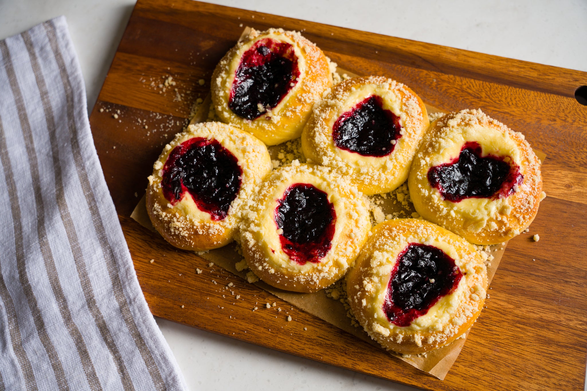 Six cherry cheese kolaches on a wooden cutting board