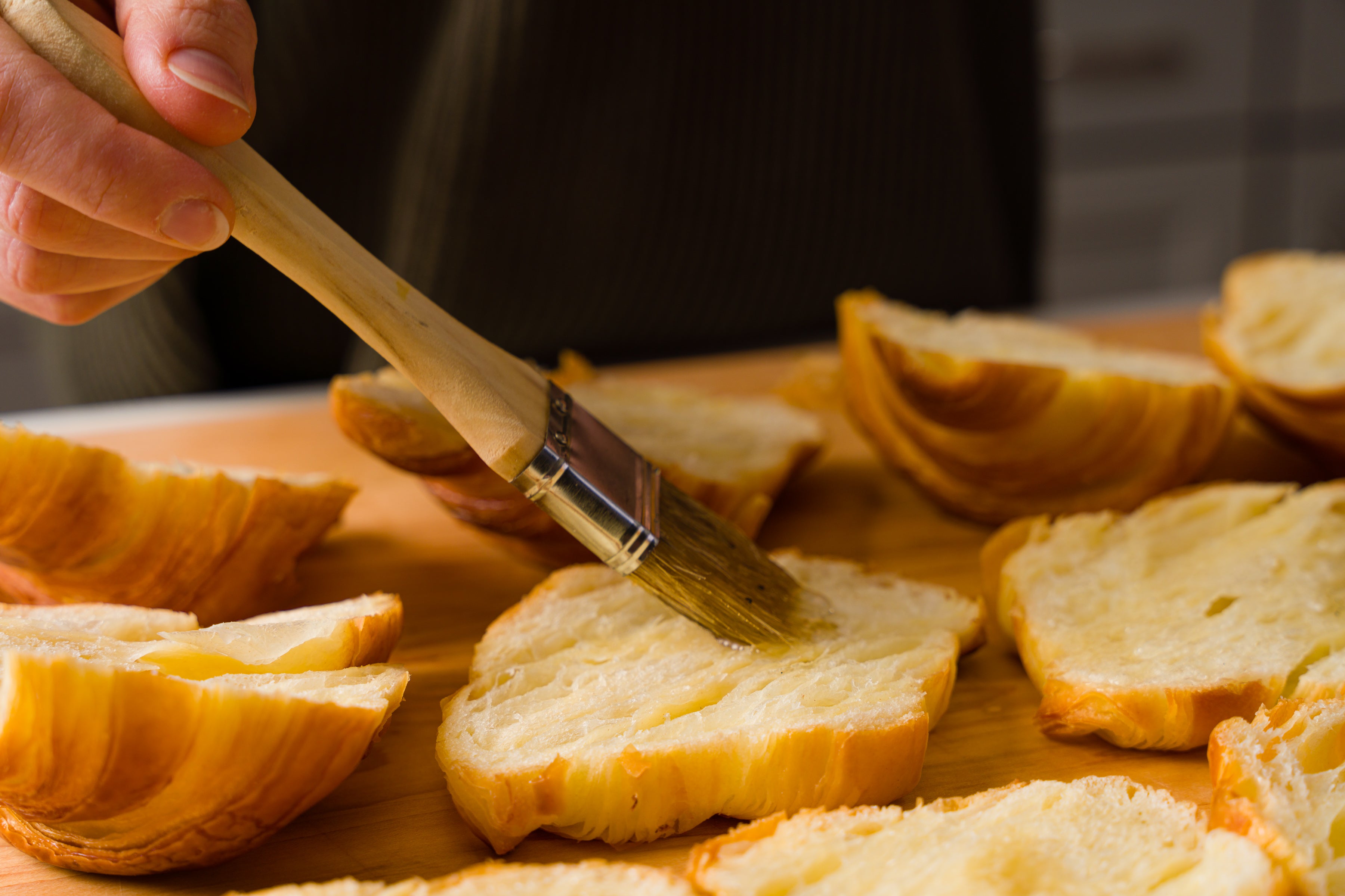 simple syrup being brushed onto cut croissant
