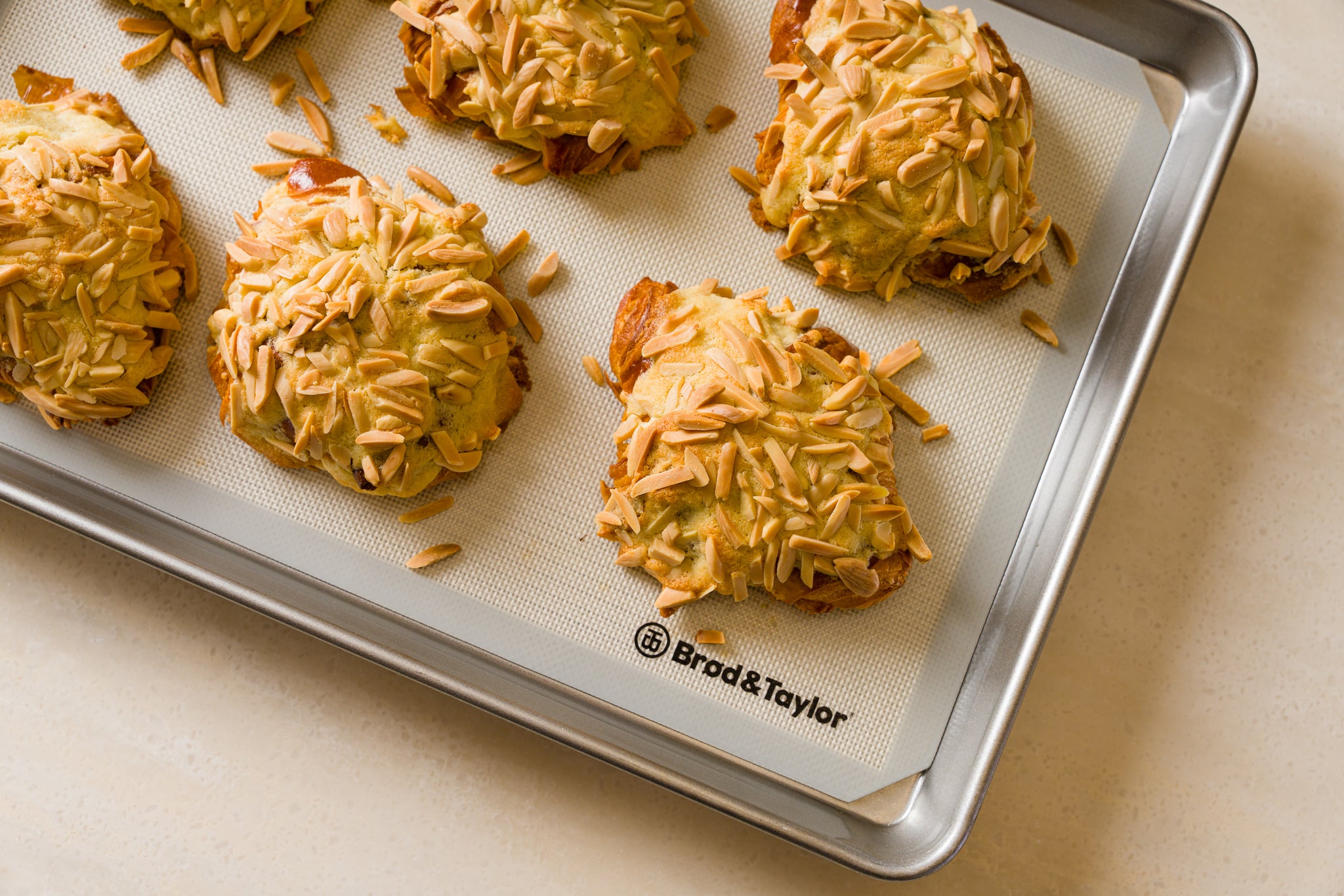 Baking tray with six freshly baked almond croissants