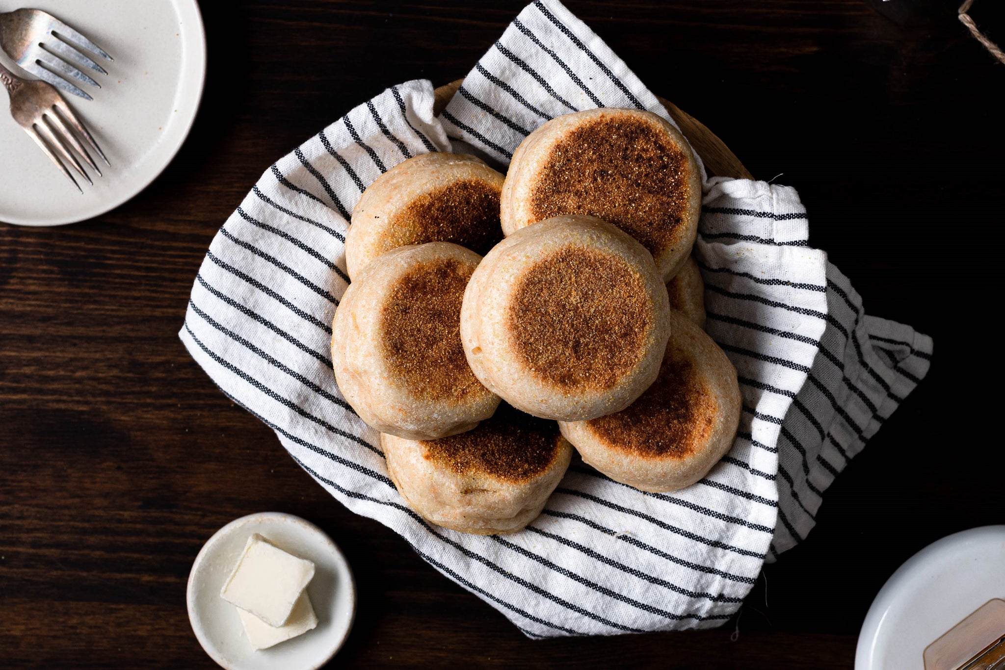 English muffins piled up on a striped kitchen town on a wooden table