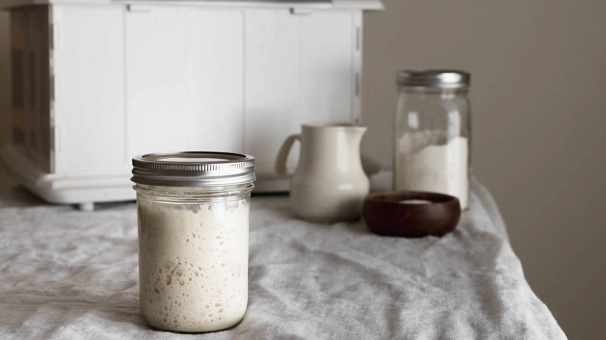 A jar of sourdough starter with the Proofer in the background