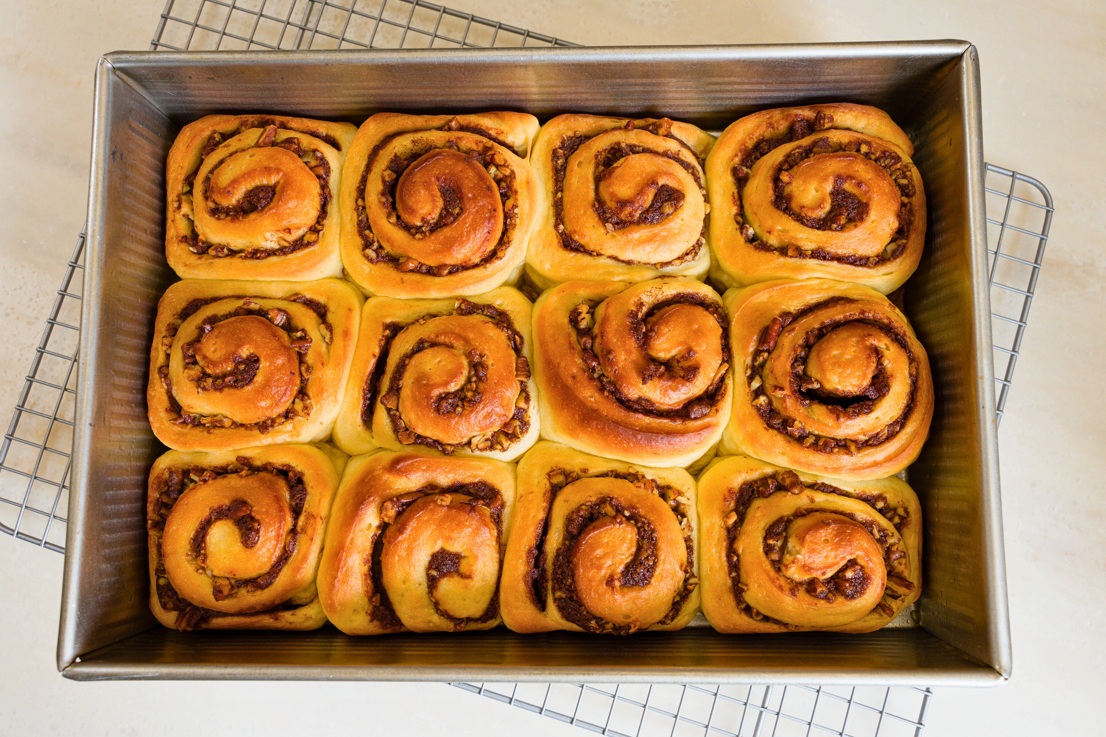 A pan of just baked cinnamon rolls just pulled from the oven sitting on a cooling rack
