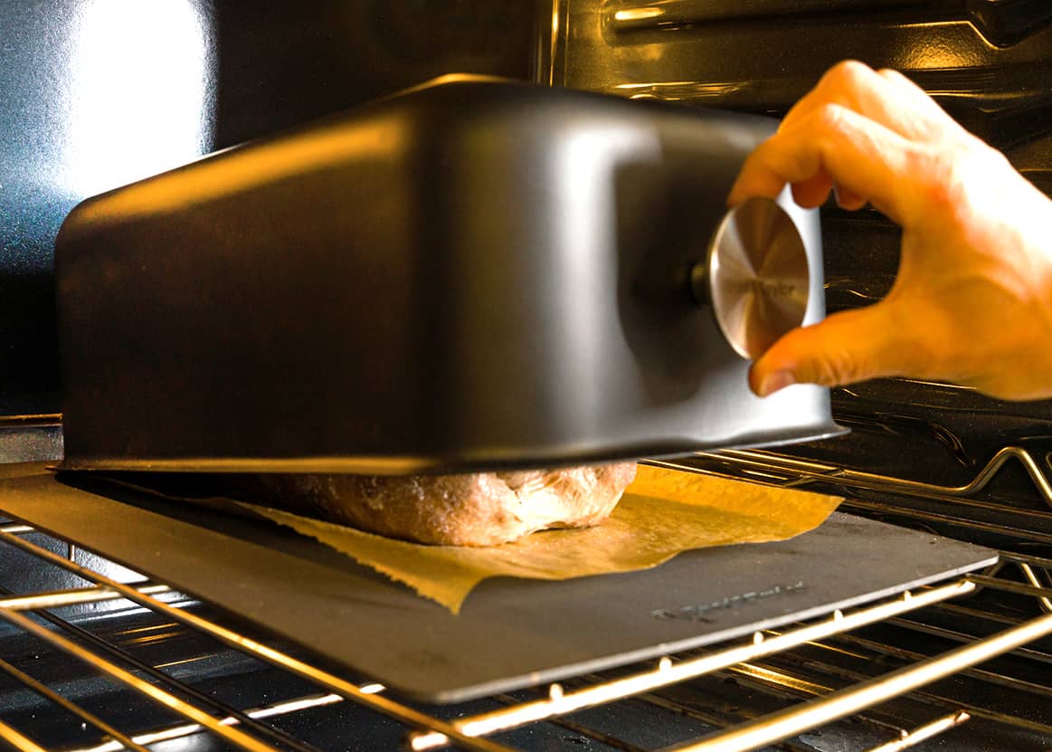 Placing the baking shell over the bread dough in the oven