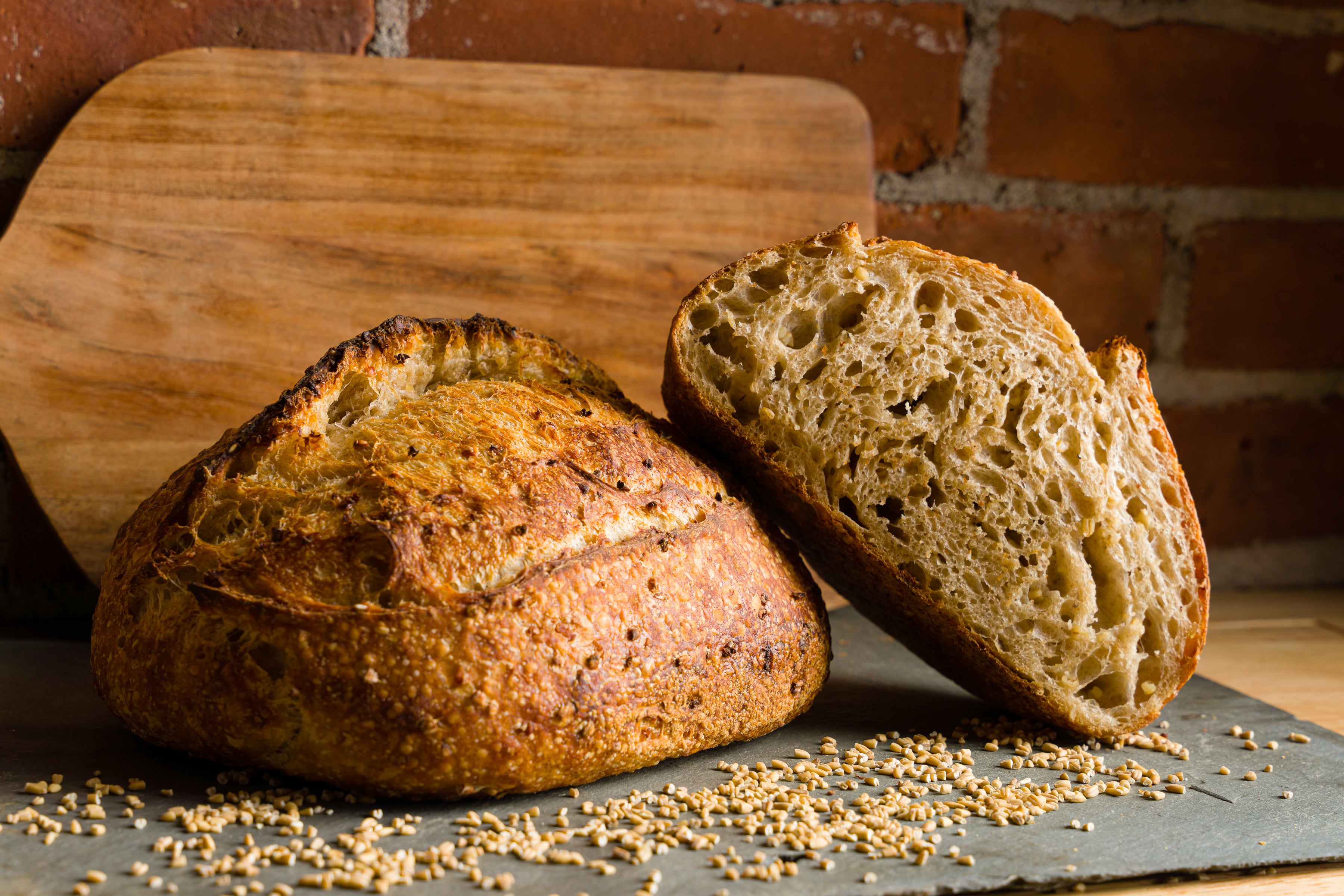 A half loaf of oat porridge bread propped up on a whole loaf.