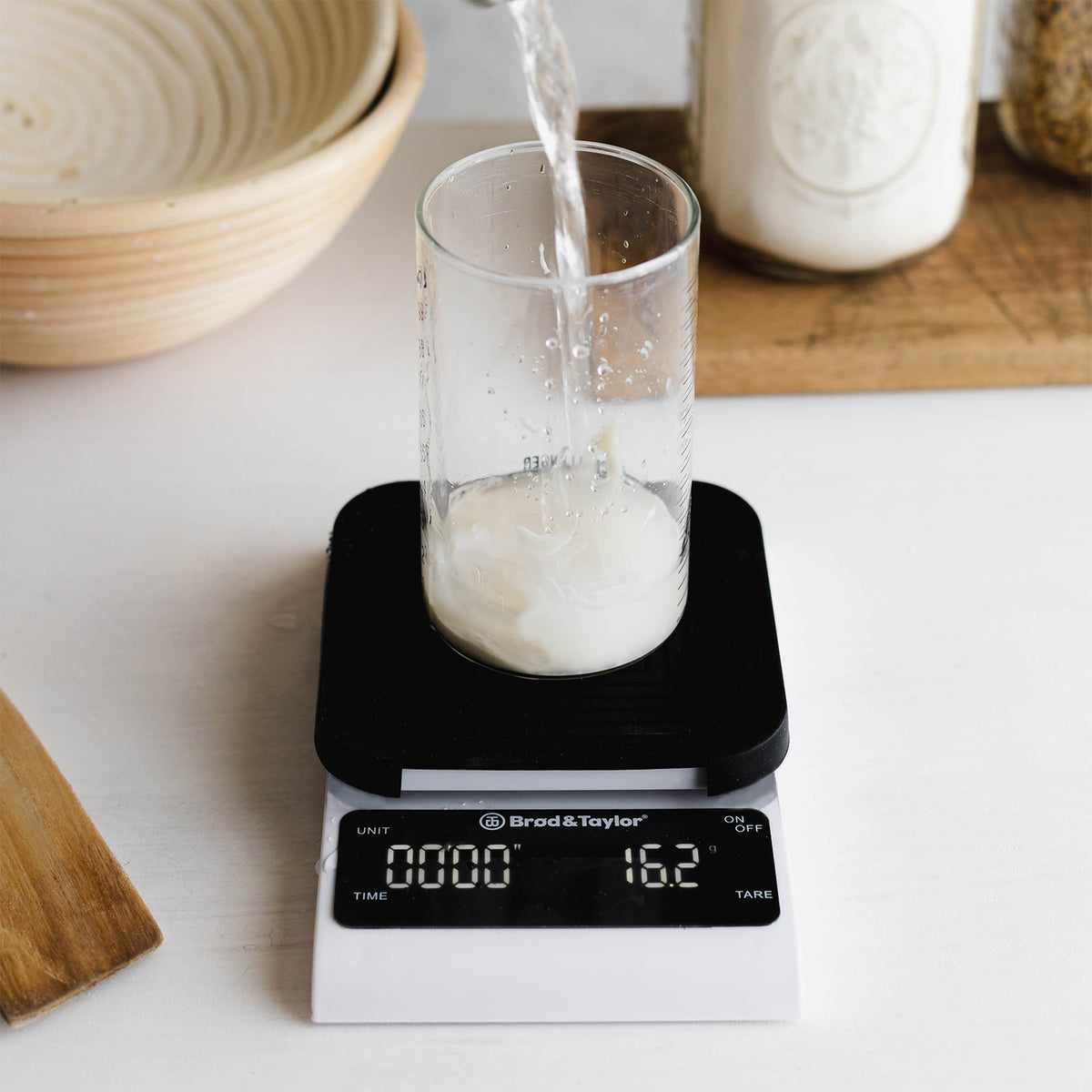 Pouring water into glass on kitchen scale, weighing ingredients