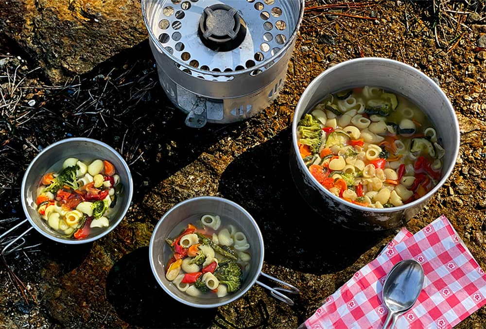 Soupe aux légumes avec un réchaud de camping et des bols