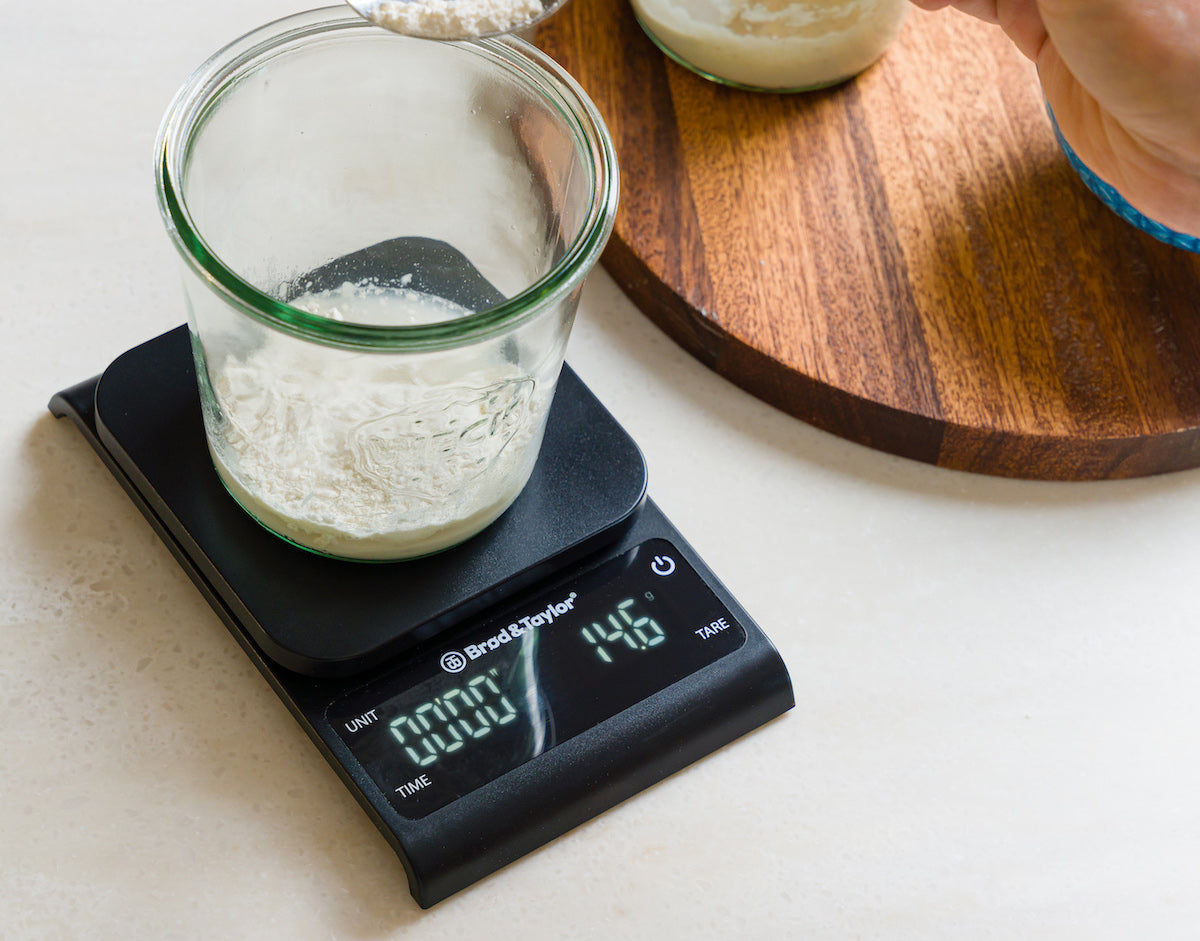 small precision kitchen scale weighing sourdough starter in glass jar